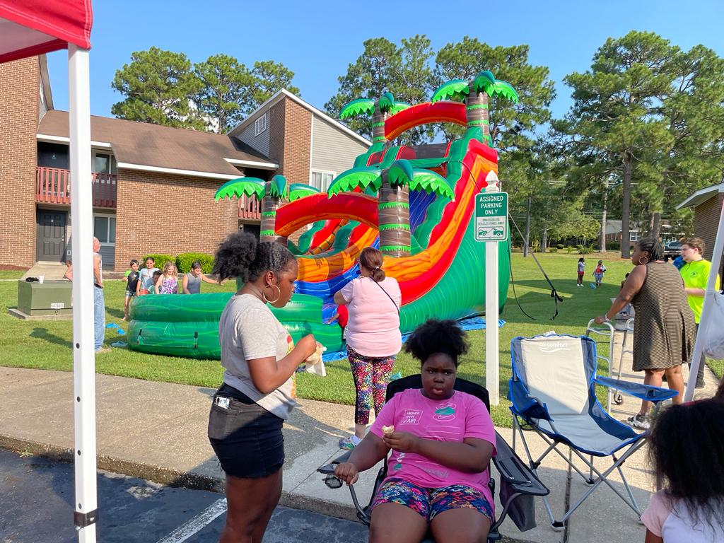 Three females from the community sitting and standing at a community event for national night out